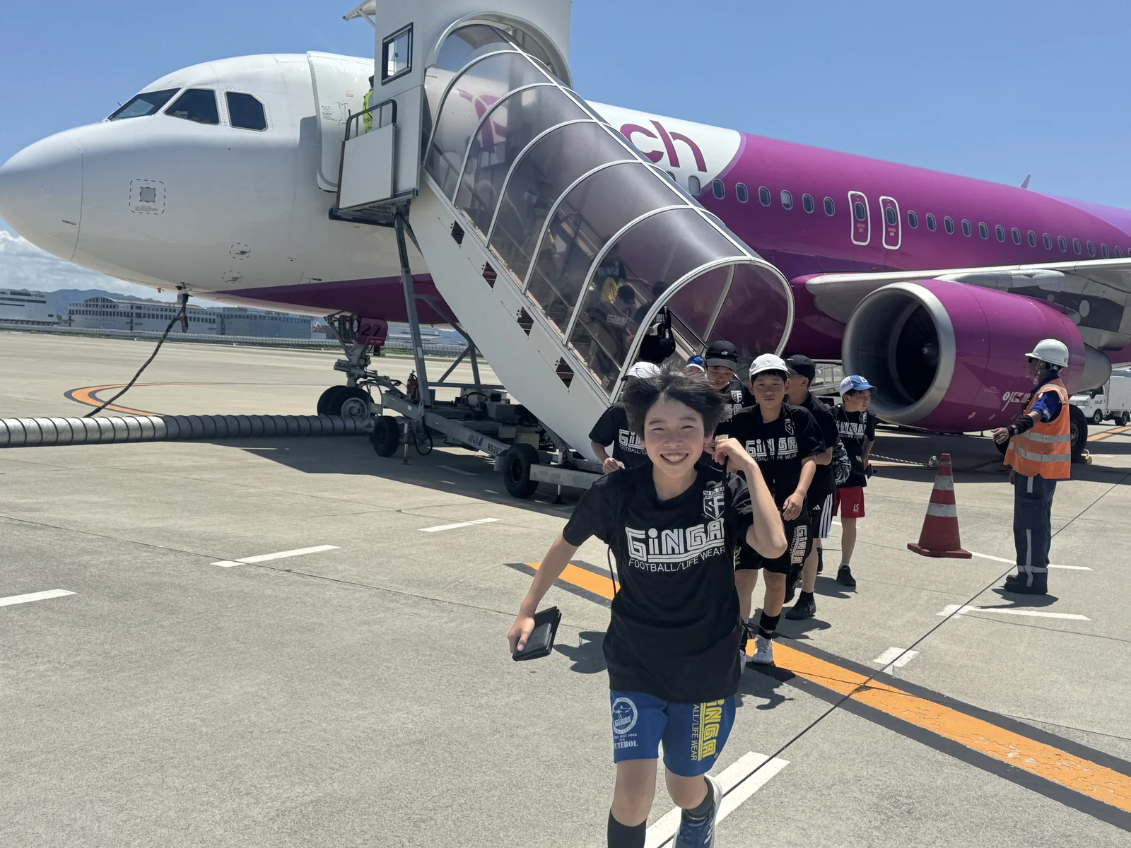 飛行機の前で笑顔を見せる真栄FCの子どもたち