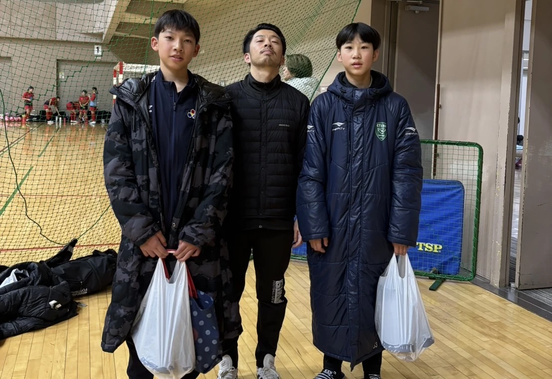 体育館で指導者と一緒に並ぶ真栄FCの仲間たち