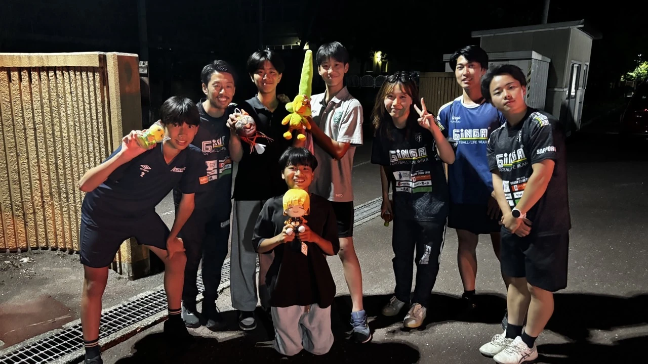 夜の屋外で一緒に記念撮影する真栄FCの仲間たち