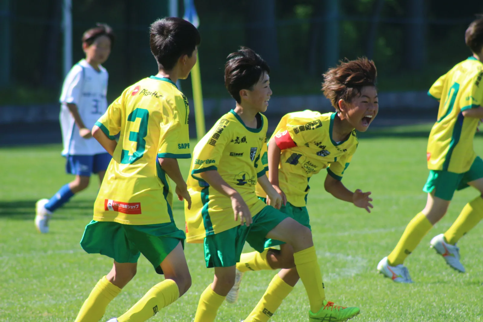 試合で声をかけ合い、笑顔を見せる真栄FCの選手たち