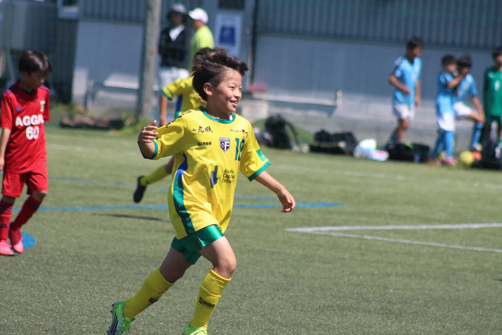笑顔でグラウンドを走る真栄FCの選手